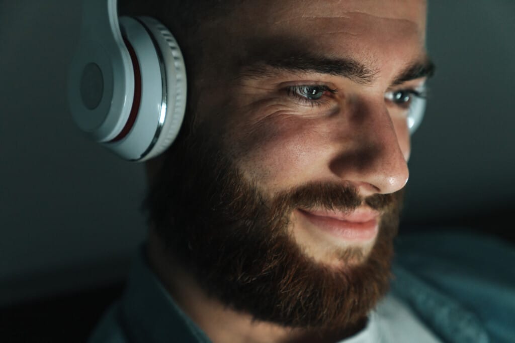 close up of a smiling bearded man wearing earphone 2023 11 27 04 54 27 utc - Verbessere deine mentale Gesundheit mit Audiotools, Meditationen und Affirmationen